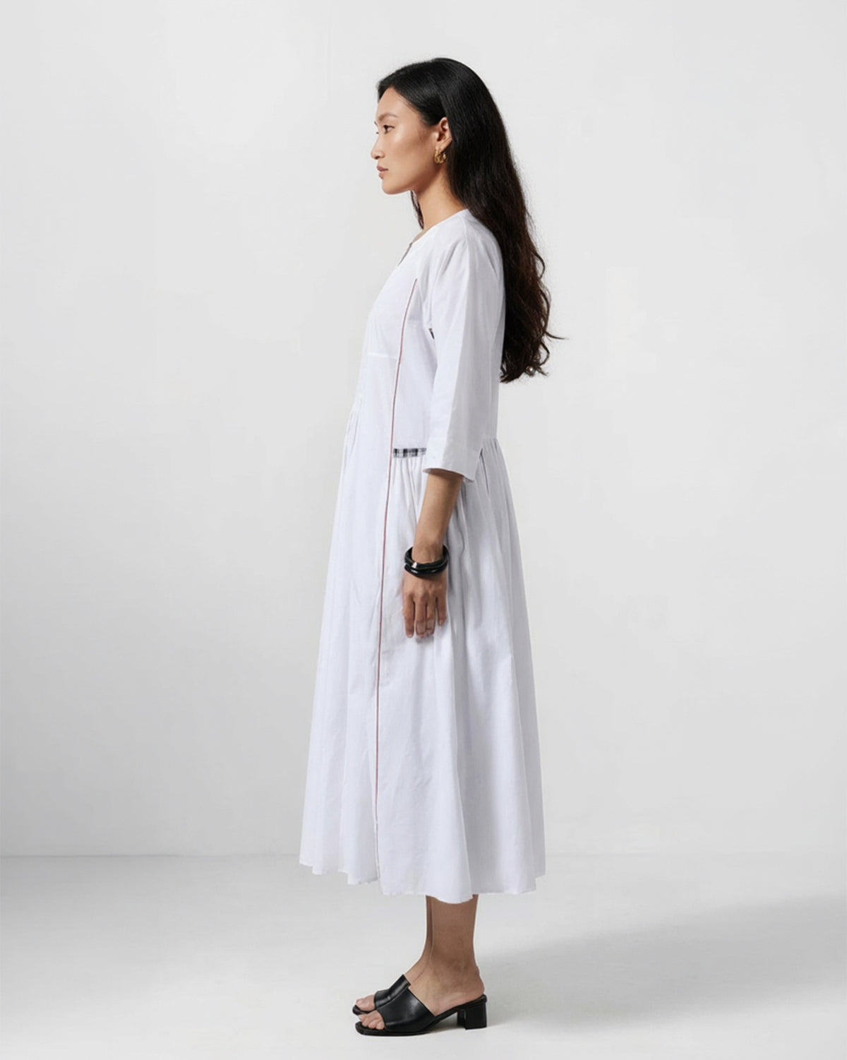 Side view of a white Torsa dress with a check waist accent and flared skirt.