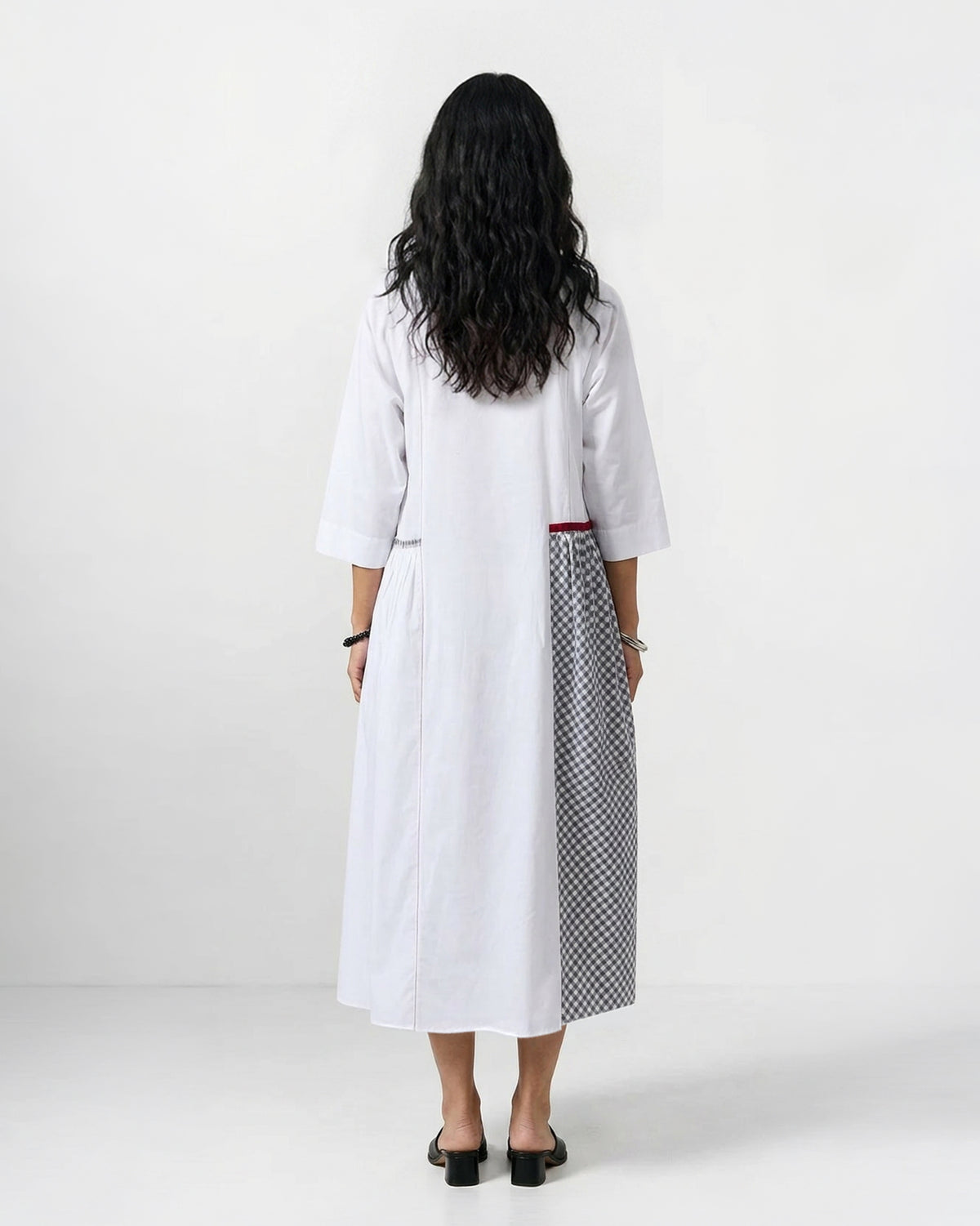 Back of a white Torsa dress with a black and white check skirt panel.