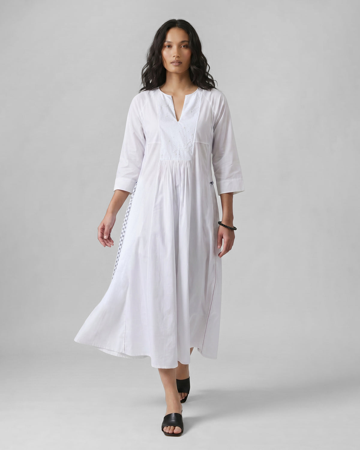 Person wearing a white embroidered Torsa dress with a flared midi skirt.