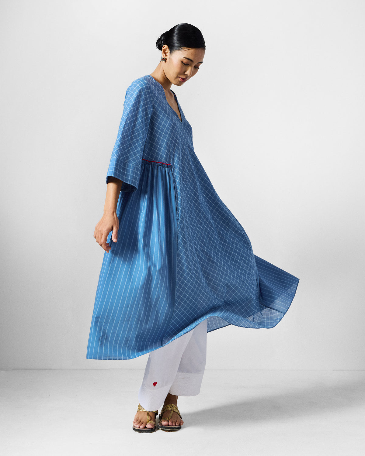 Person wearing a blue-and-white check Giri kurta with flared panels and a V-neck.