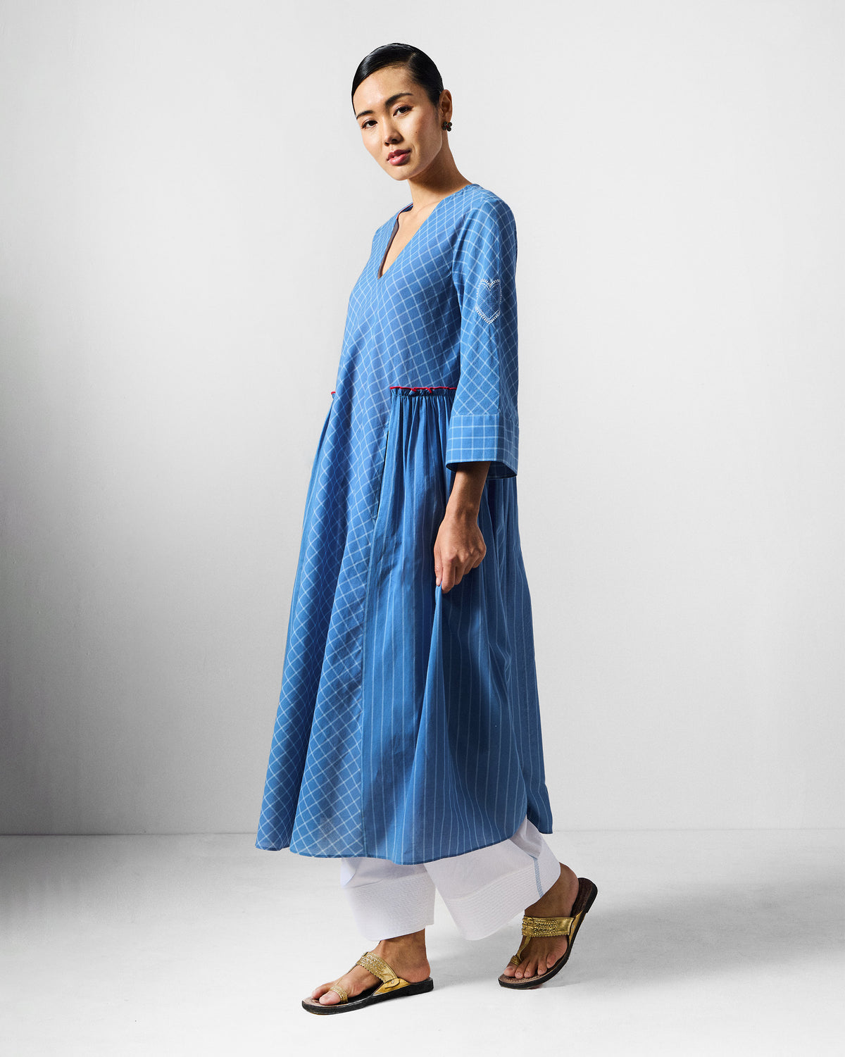 Side view of a blue-and-white check Giri kurta with side pleats and a sleeve heart.