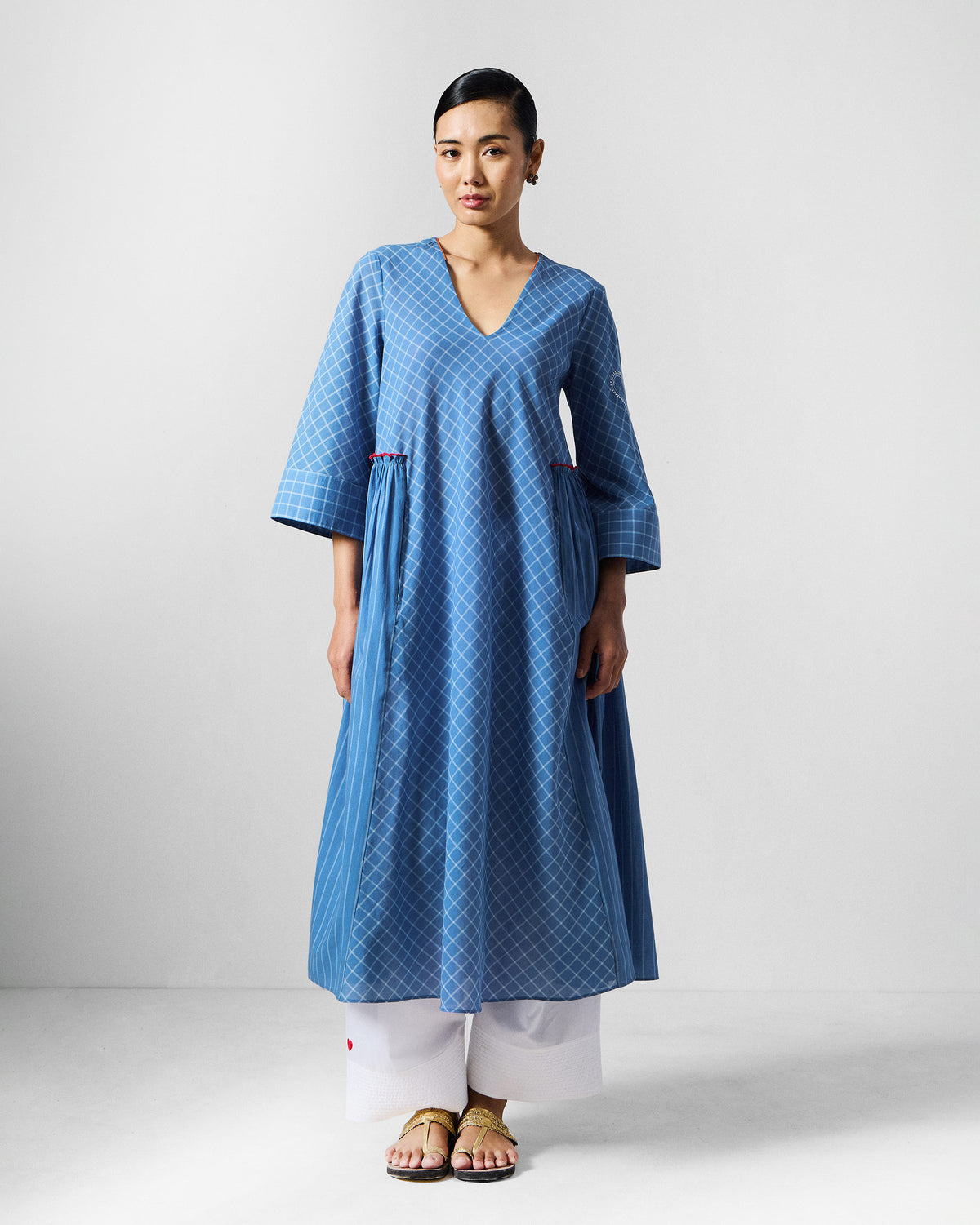 Person wearing a blue-and-white check Giri kurta with a V-neck and side pleats.