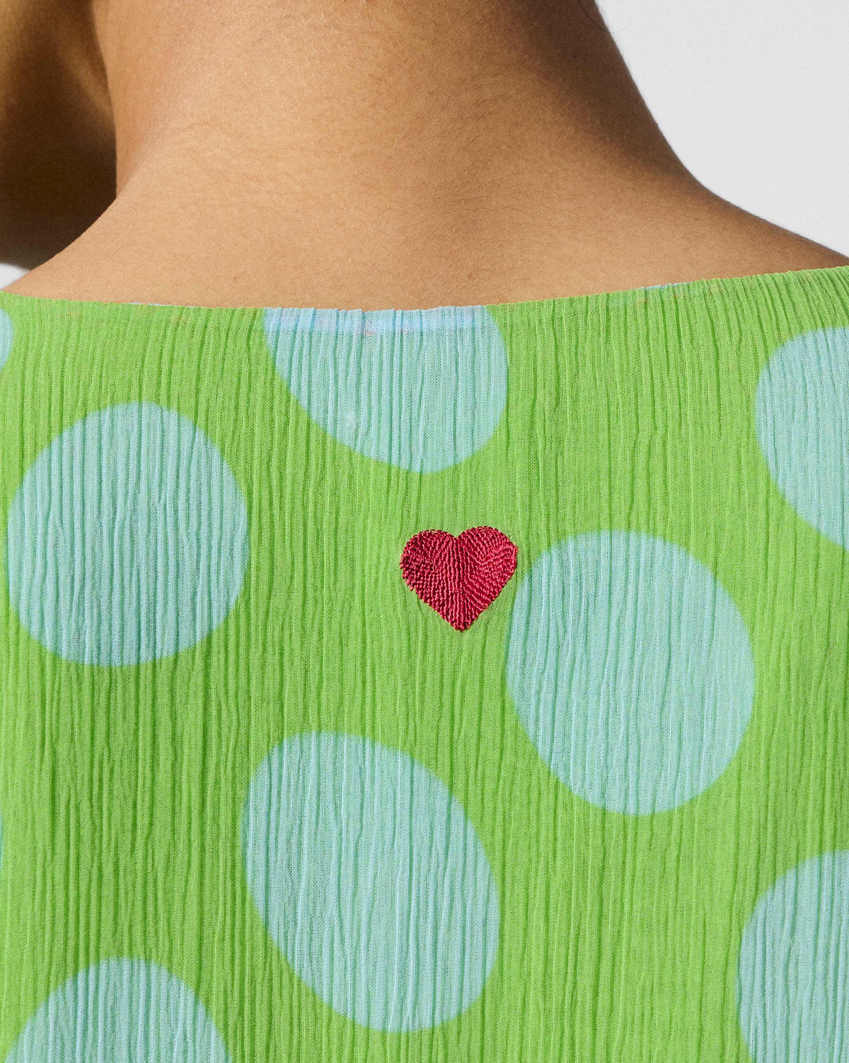 Close-up of a red embroidered heart on a green and blue dotted kurta.