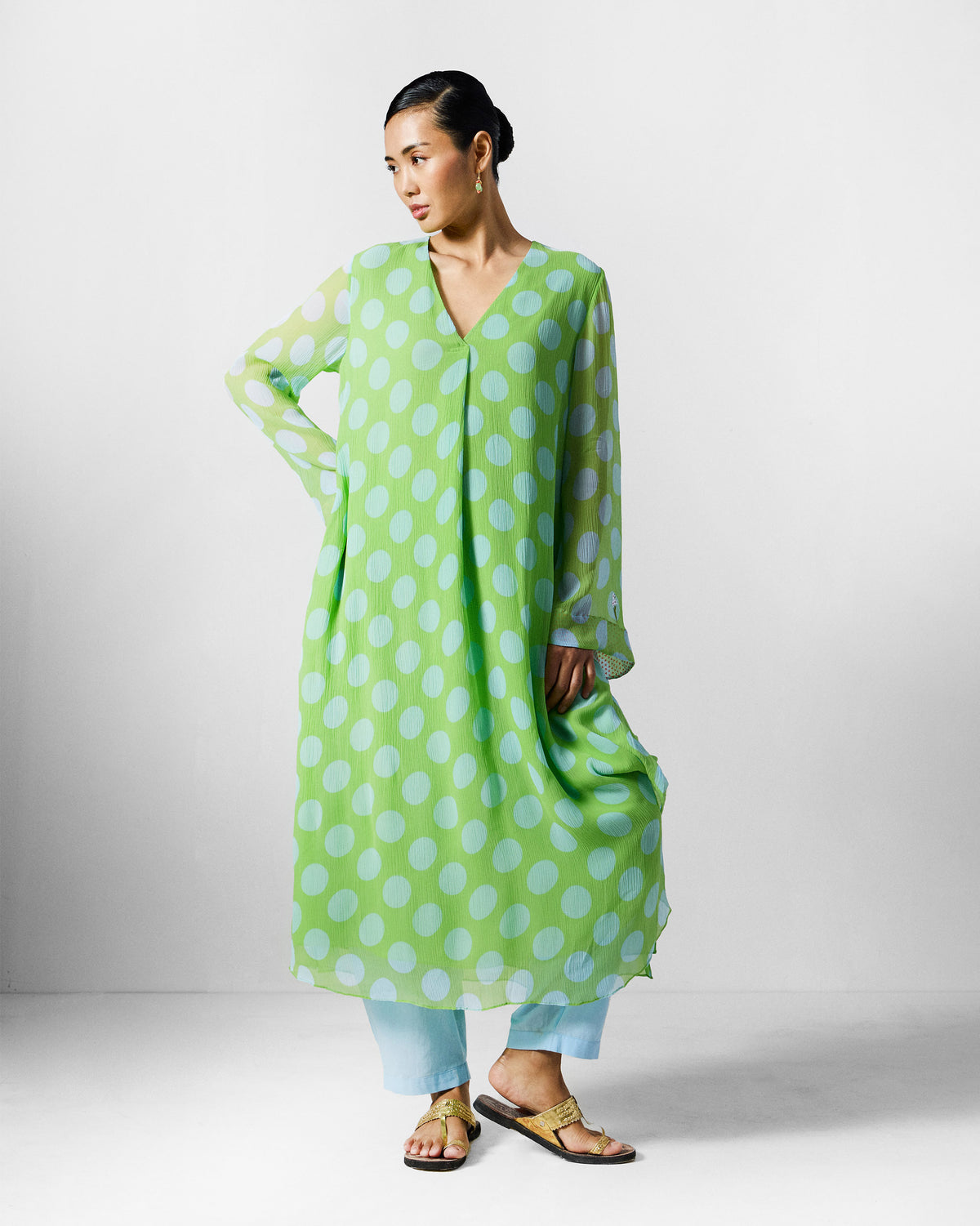Person wearing a green and blue dotted kurta with a centre front pleat.