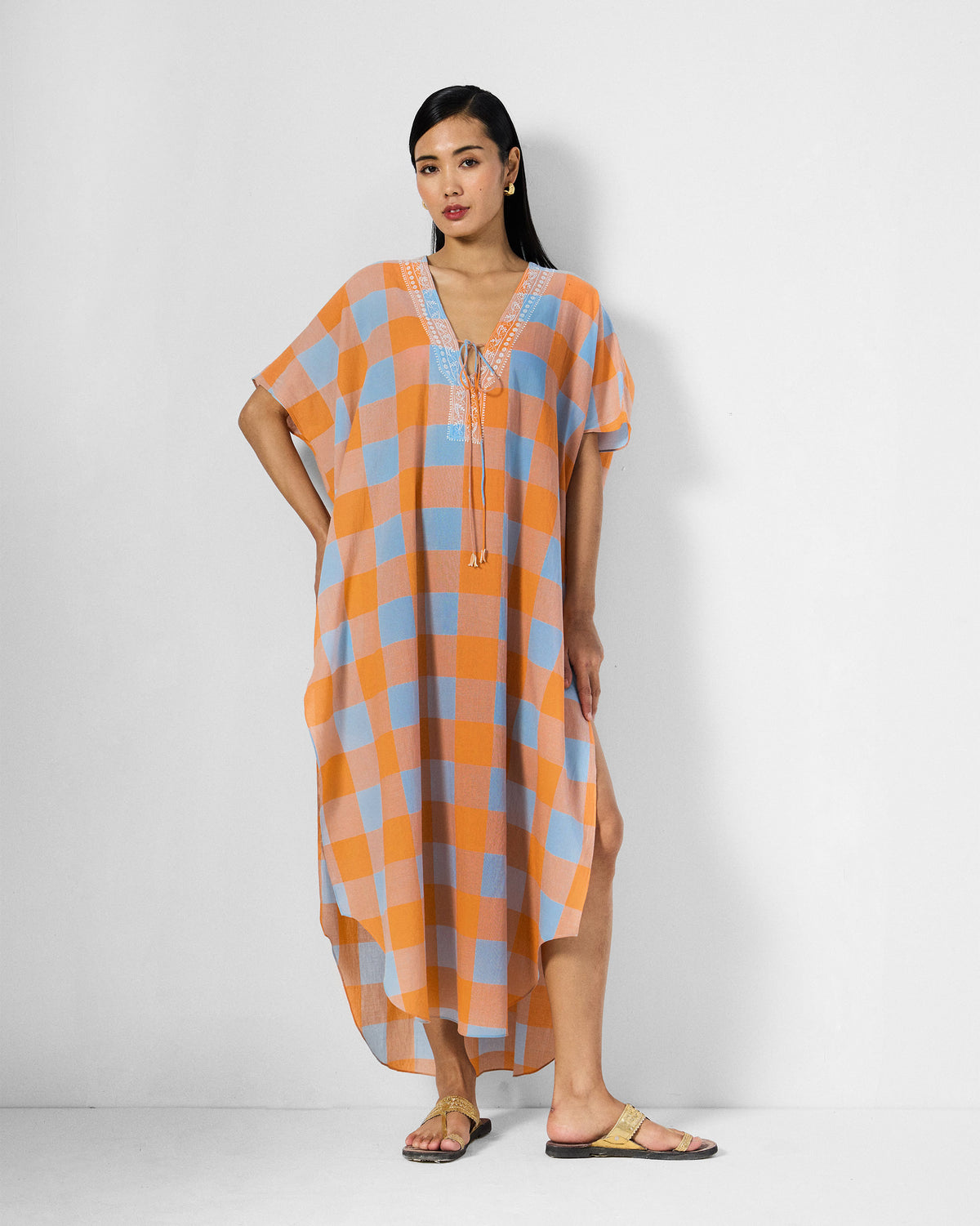 Person wearing an orange and ice-blue check Vaya Kaftan with a deep V-neck.