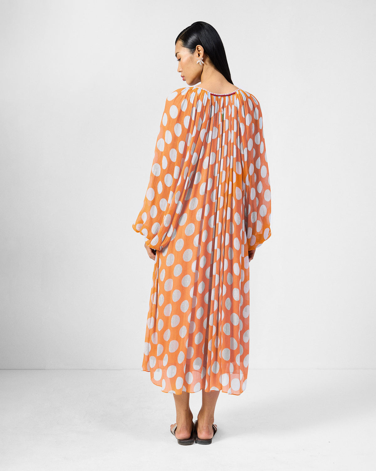 Back of an orange Sara kaftan with white dots and full sleeves.