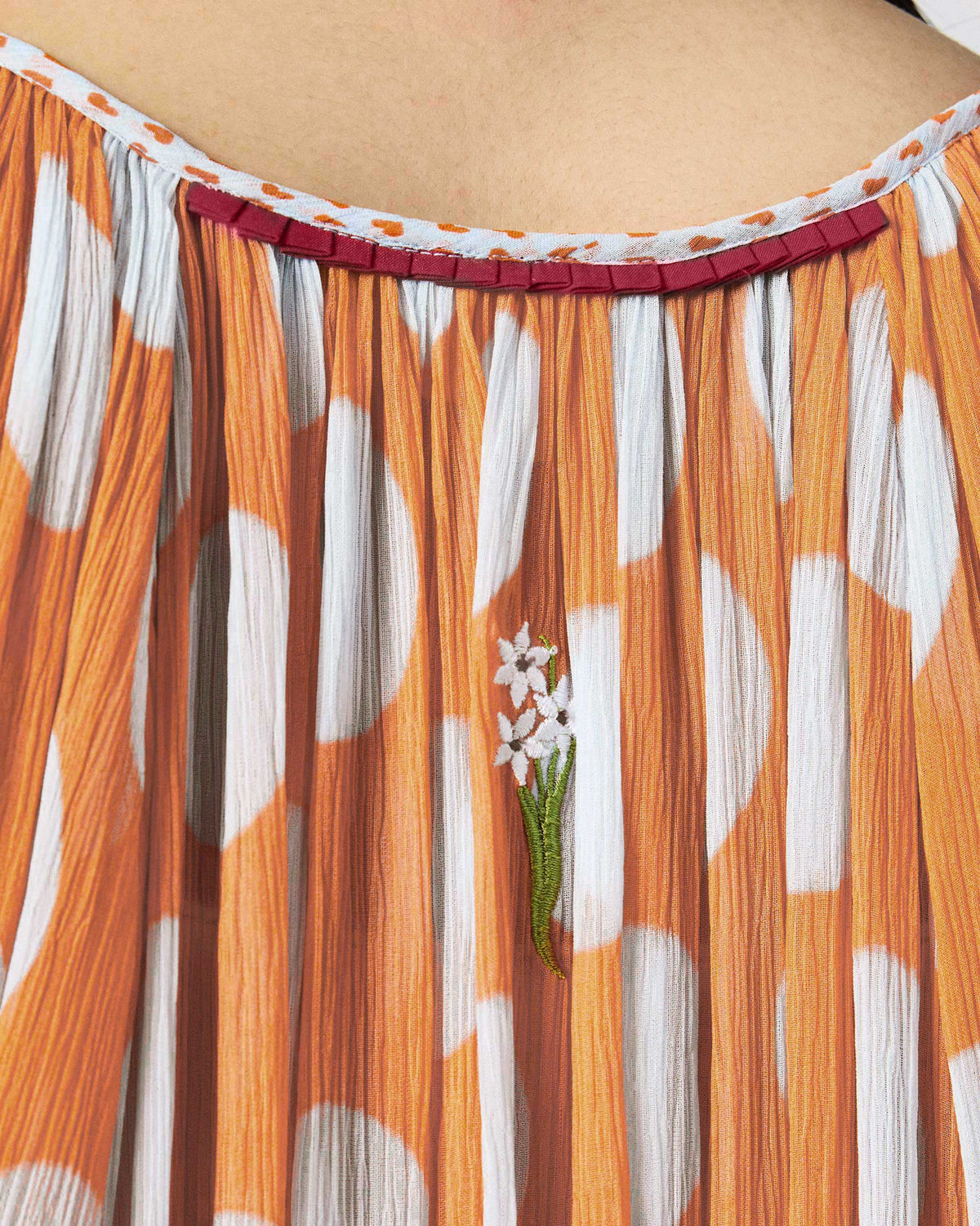 Close-up of floral embroidery on an orange dotted Sara kaftan neckline.