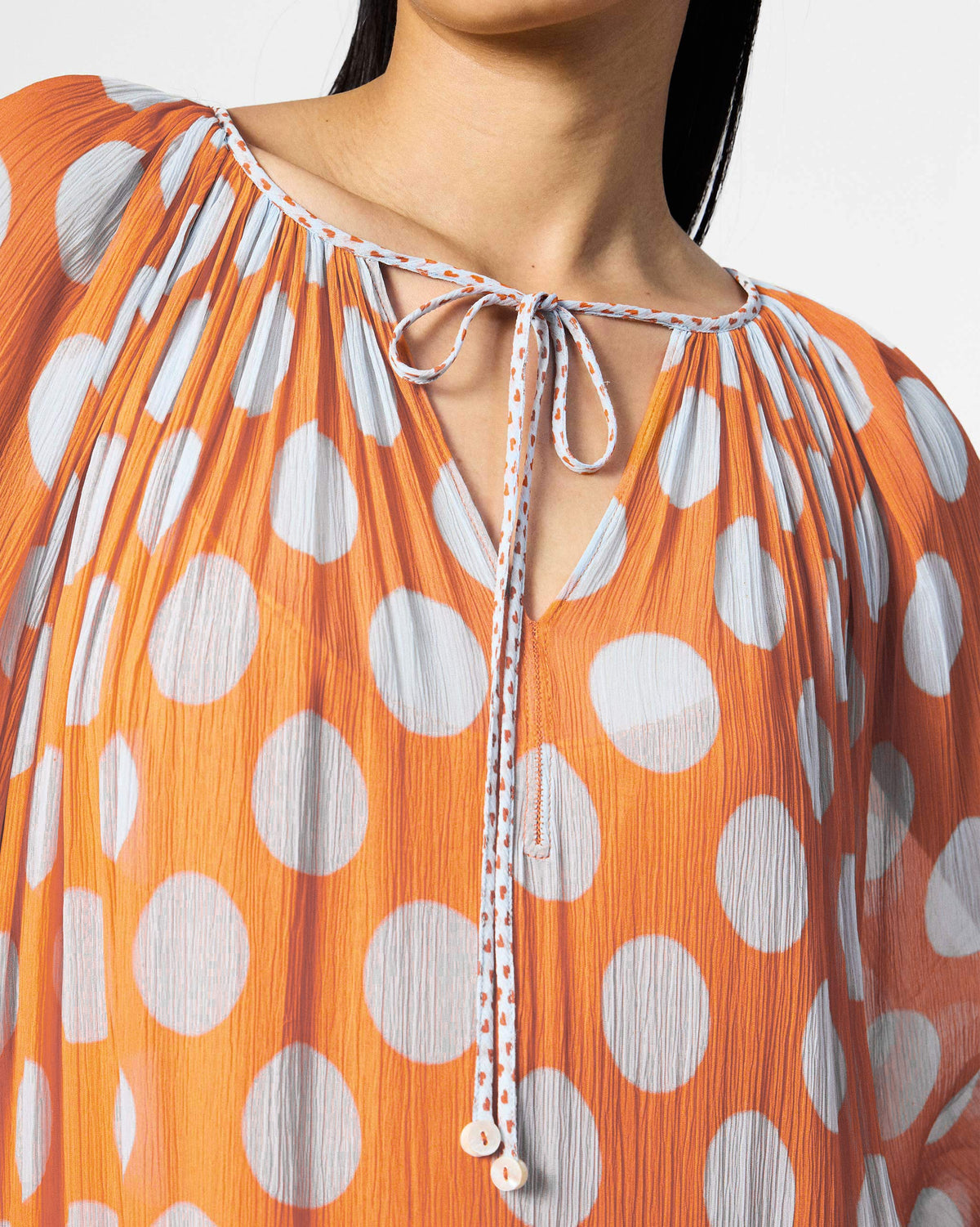 Close-up of the drawstring neckline on an orange dotted Sara kaftan.