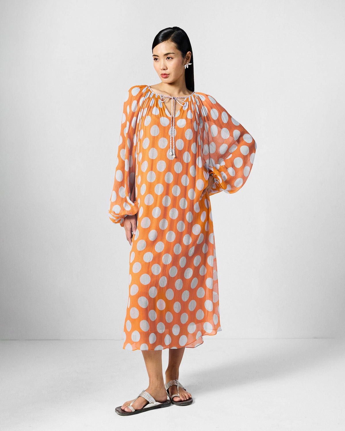 Person wearing an orange Sara kaftan with white dots and balloon sleeves.