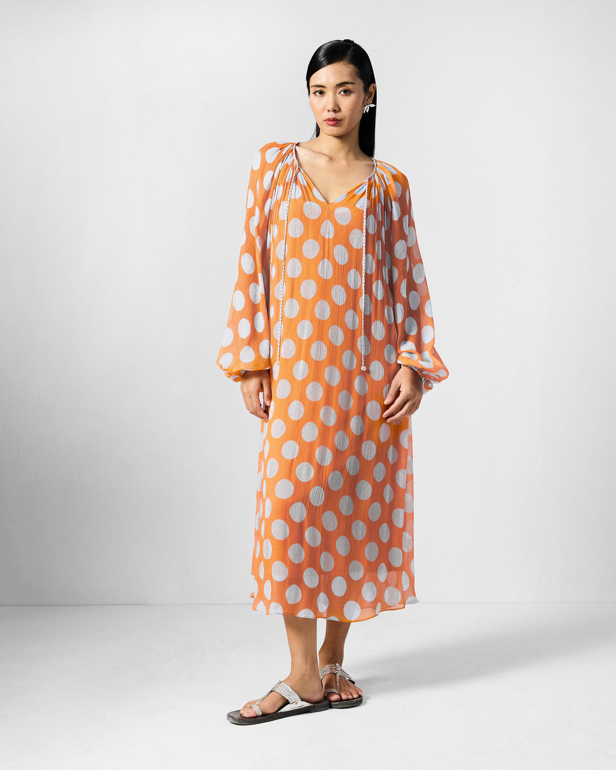 Front view of an orange Sara kaftan with white dots and neck ties.