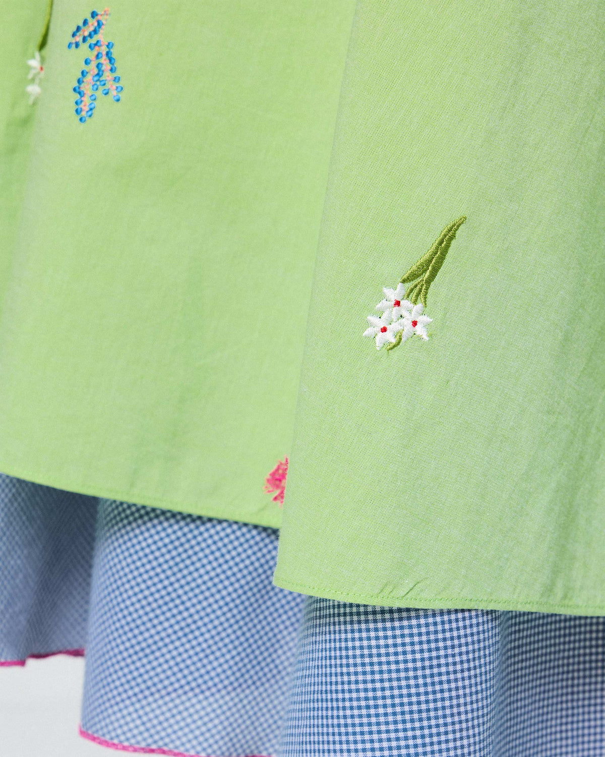 Close-up of the Ezra Dress hem with white embroidered flowers and a gingham underlayer.