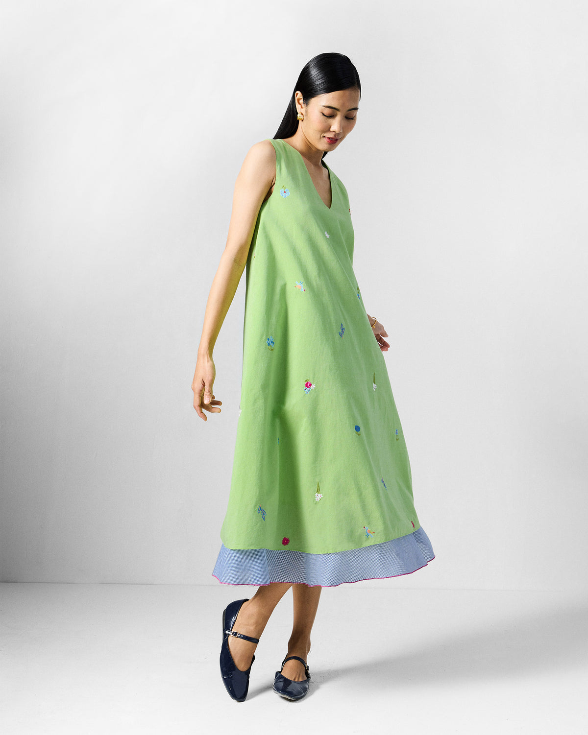 Person wearing a lime green Ezra Dress with small embroidered motifs.