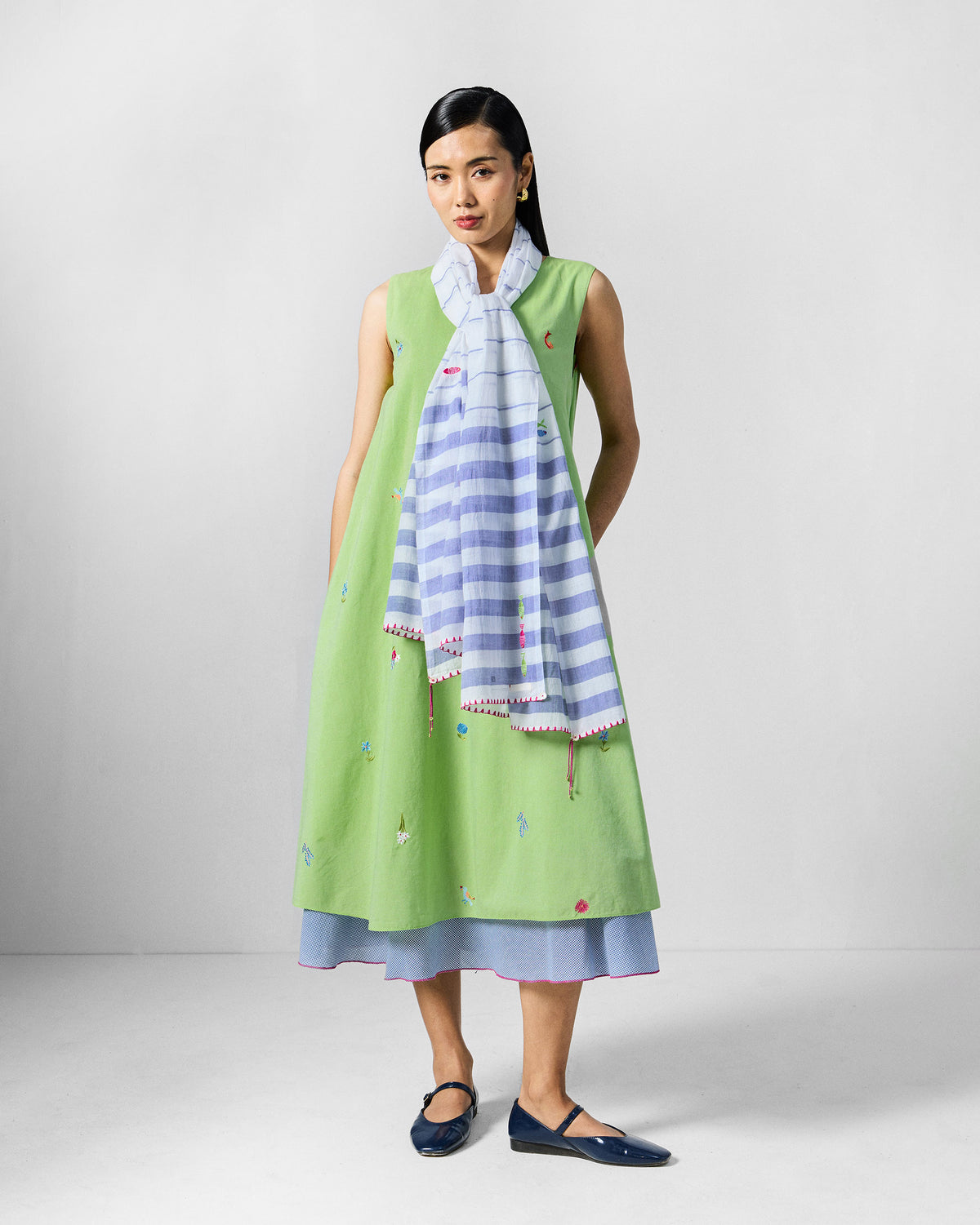 Person wearing a lime green Ezra Dress with a striped scarf draped over it.