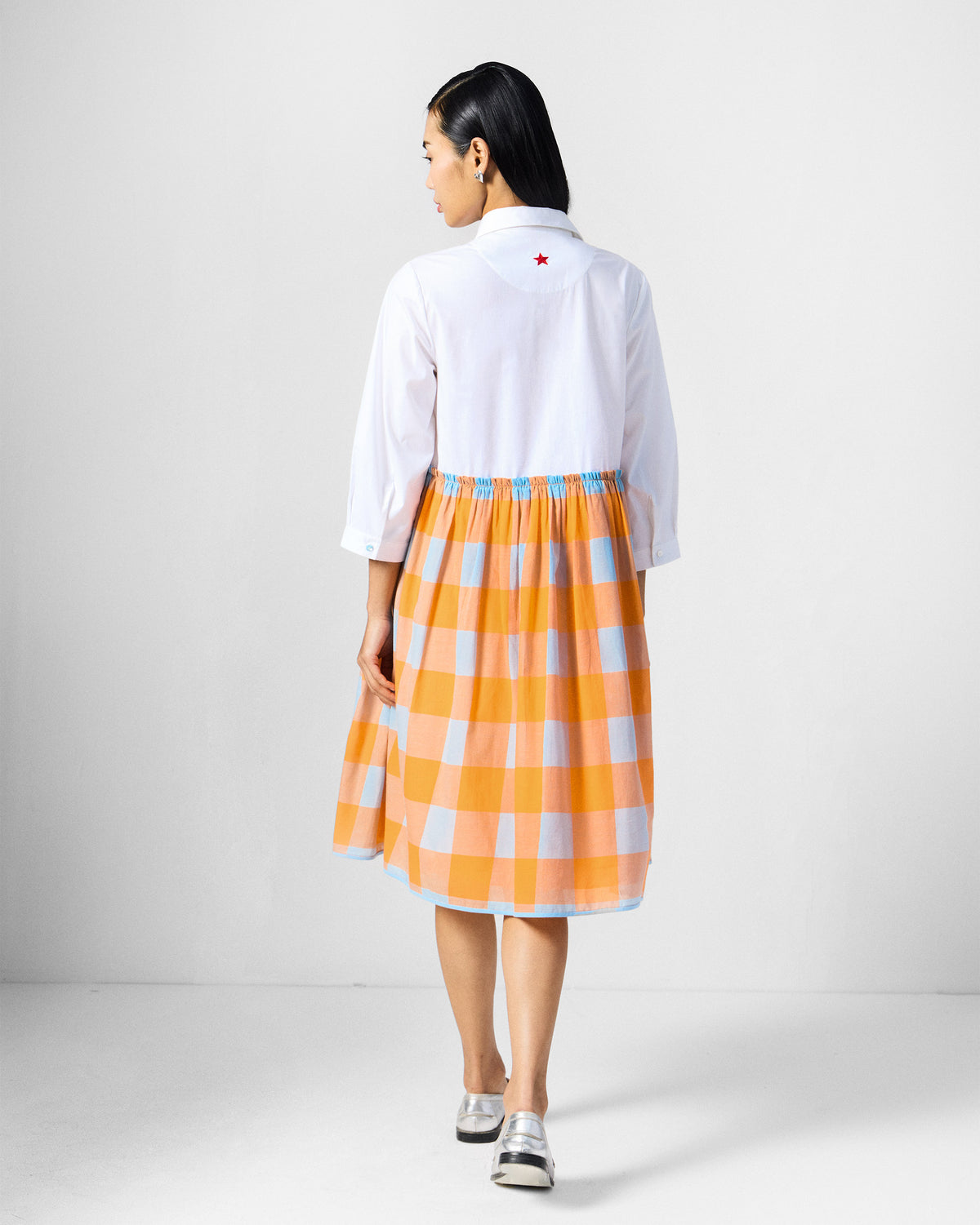 Back of a white dress with a red star and checked skirt.