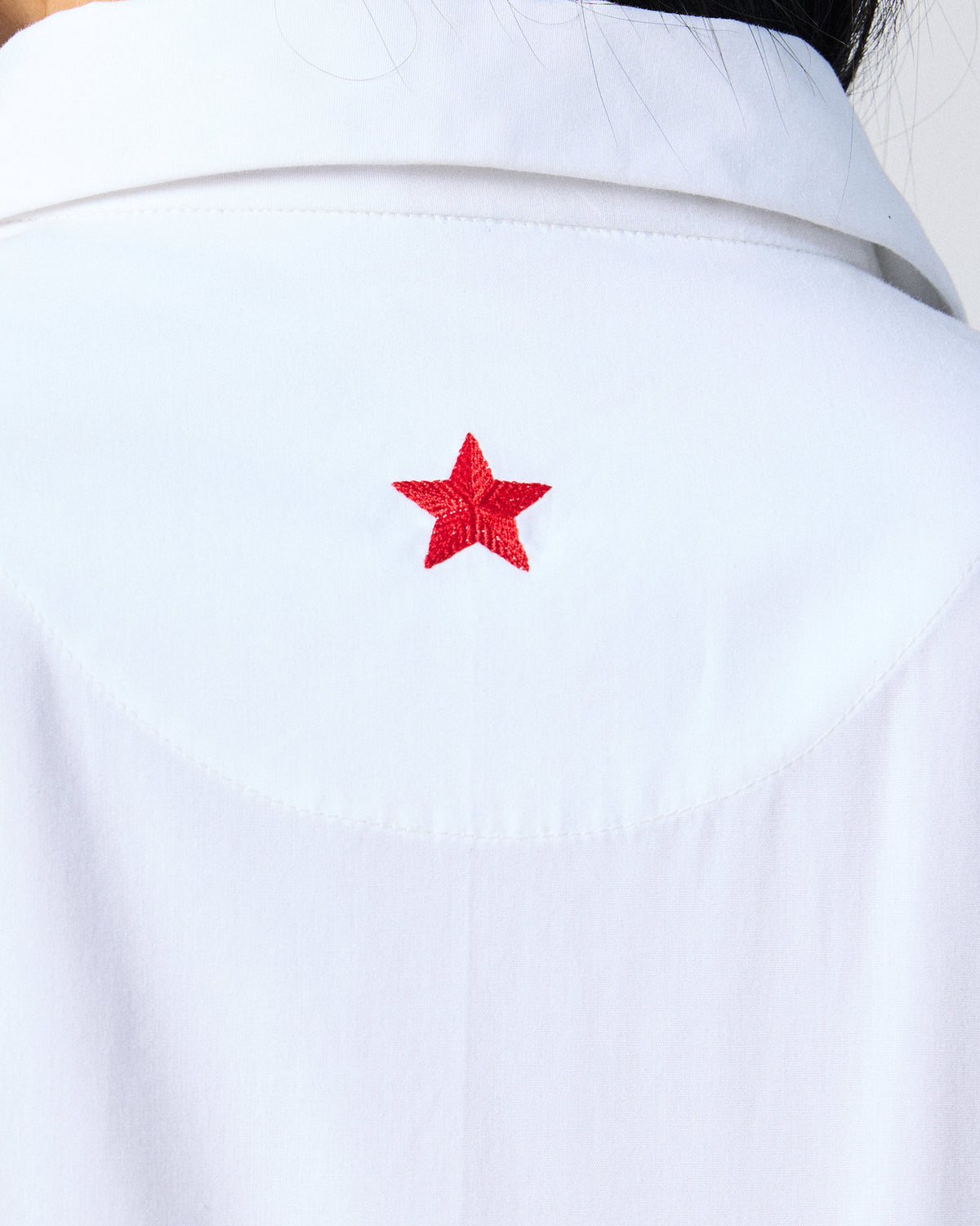 Close-up of a white dress with a red embroidered star.