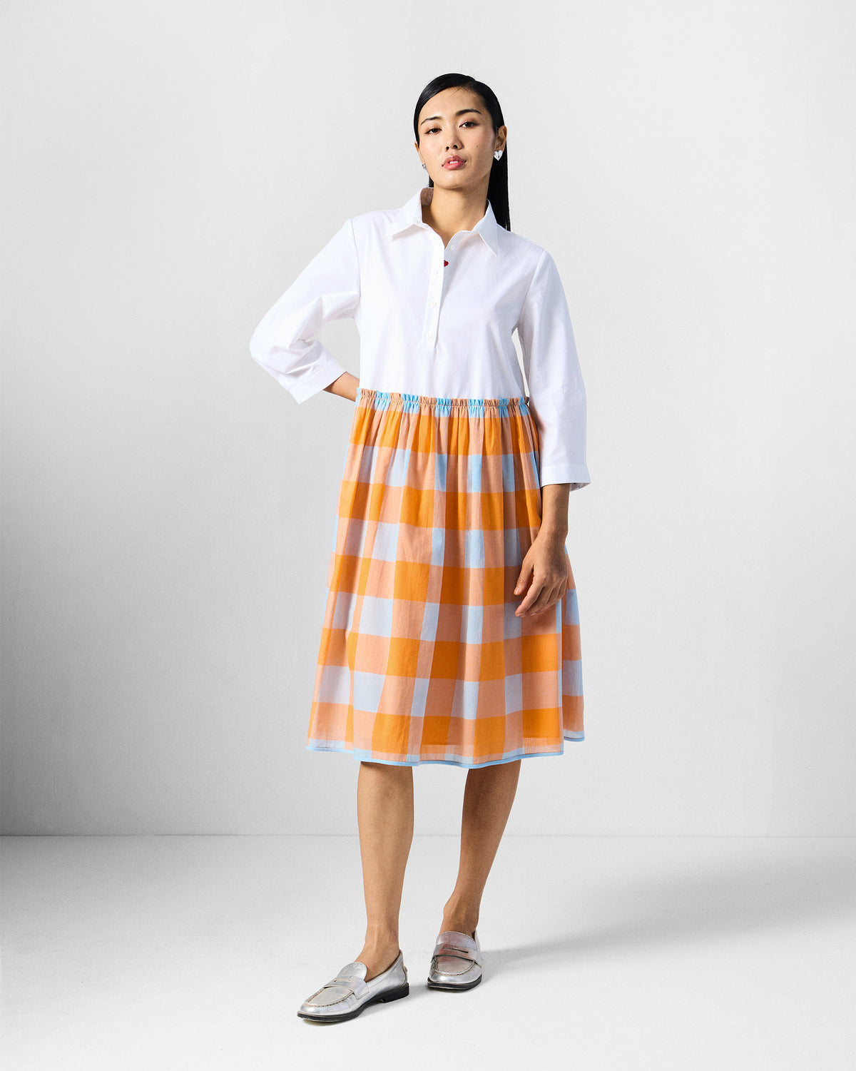 Person wearing a knee-length dress with an orange checked skirt.
