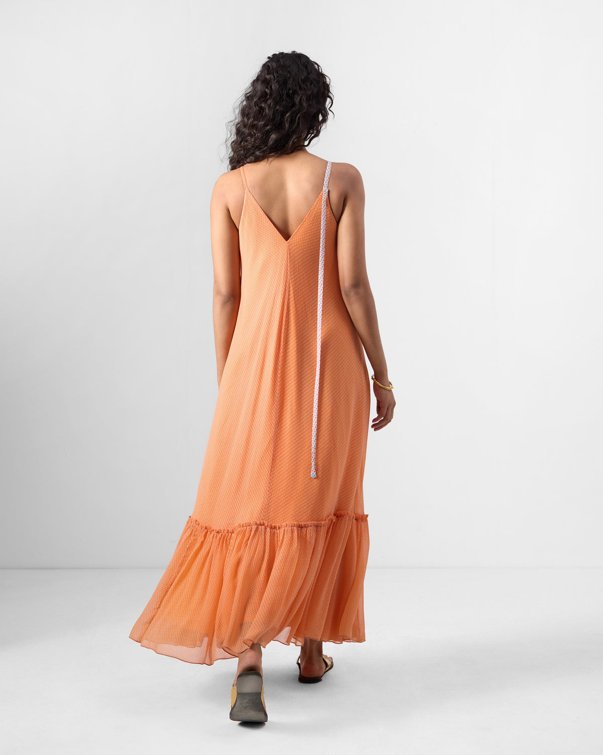 Back of an orange Luma dress with a deep V and hanging dori.