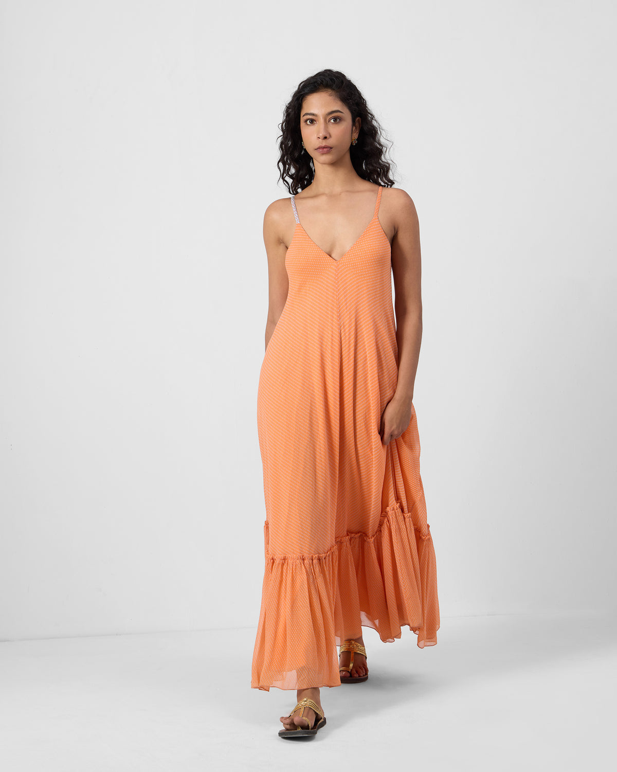Person wearing an orange Luma dress with a deep V-neck and ruffle hem.