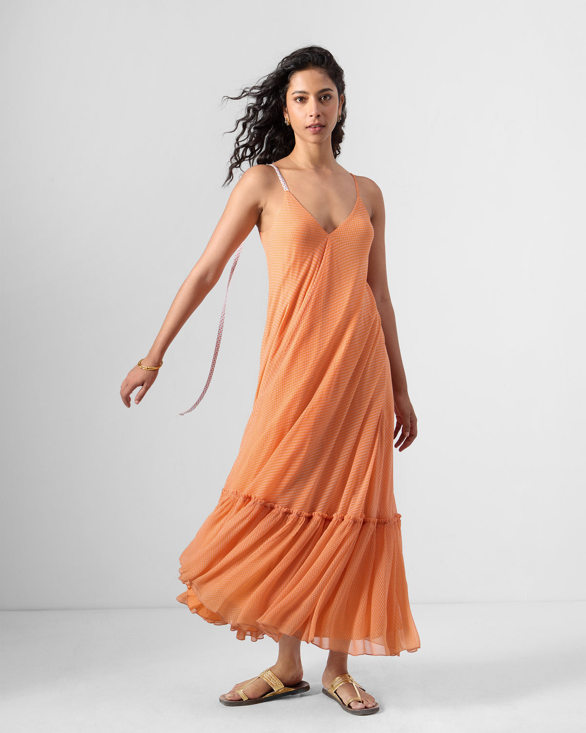 Person wearing an orange Luma dress with a trailing dori at the strap.