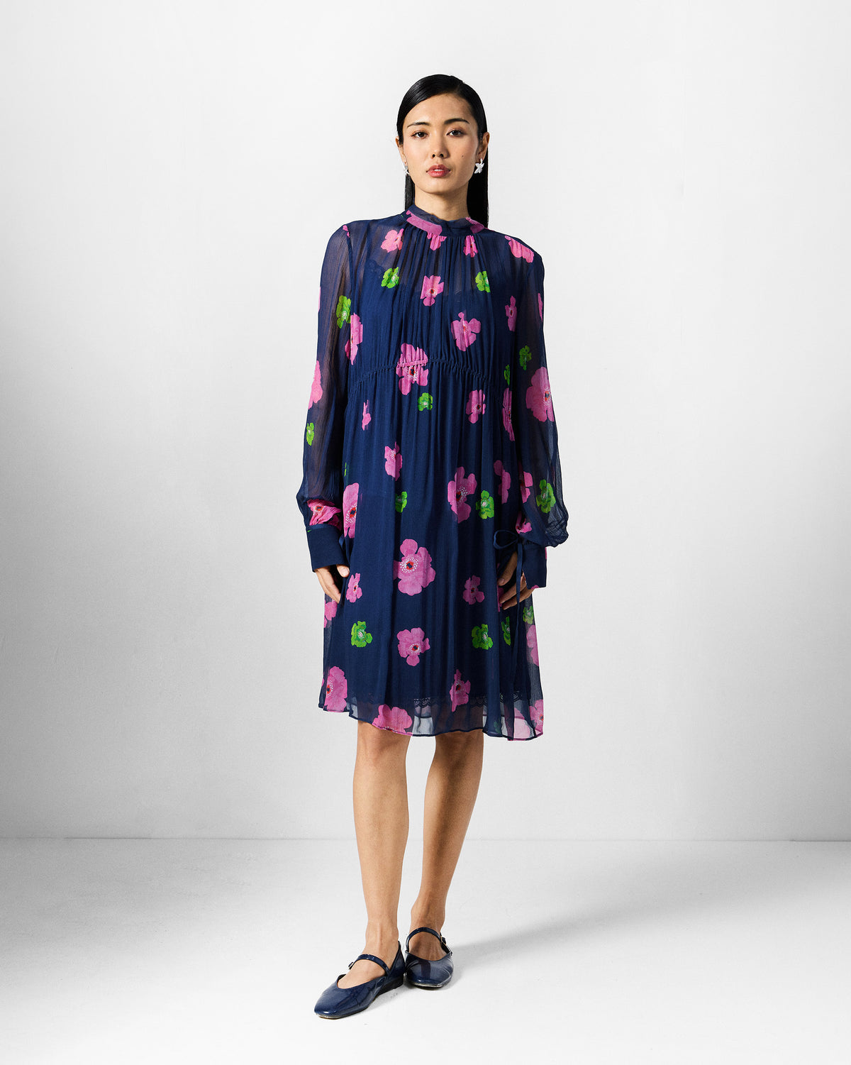 Person wearing a navy floral Raya dress with a high collar.