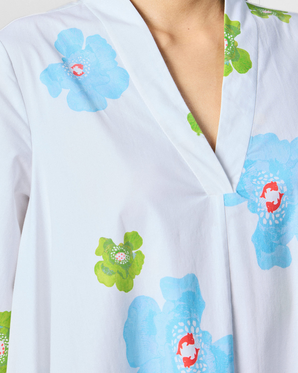 Close-up of blue poppies on the V-neck of a white Nava Dress.