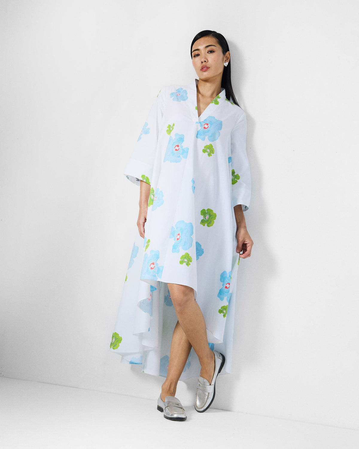 Person wearing a white Nava Dress with blue poppies and a high-low hem.
