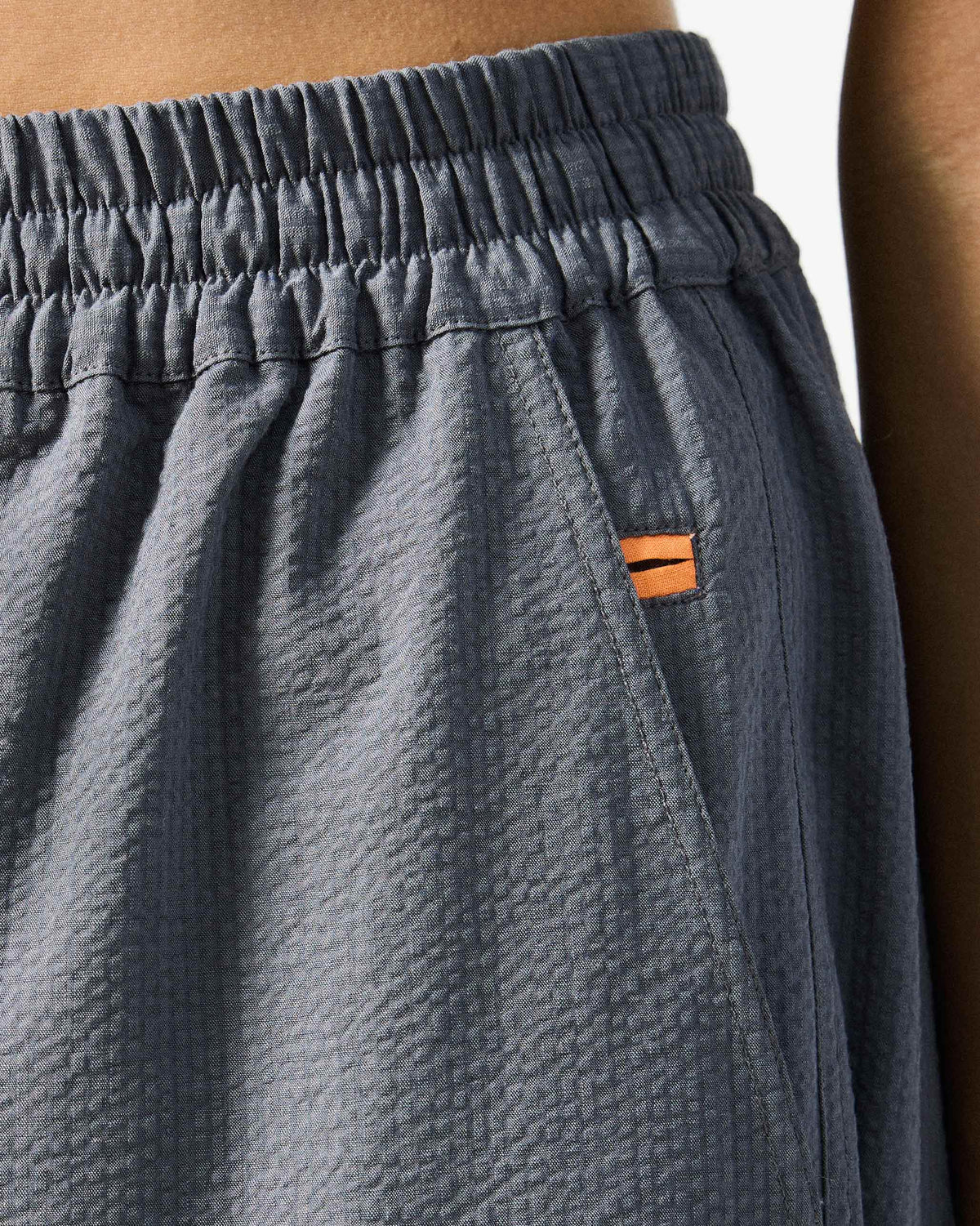 Close-up of charcoal joggers waistband with an orange pocket tab.