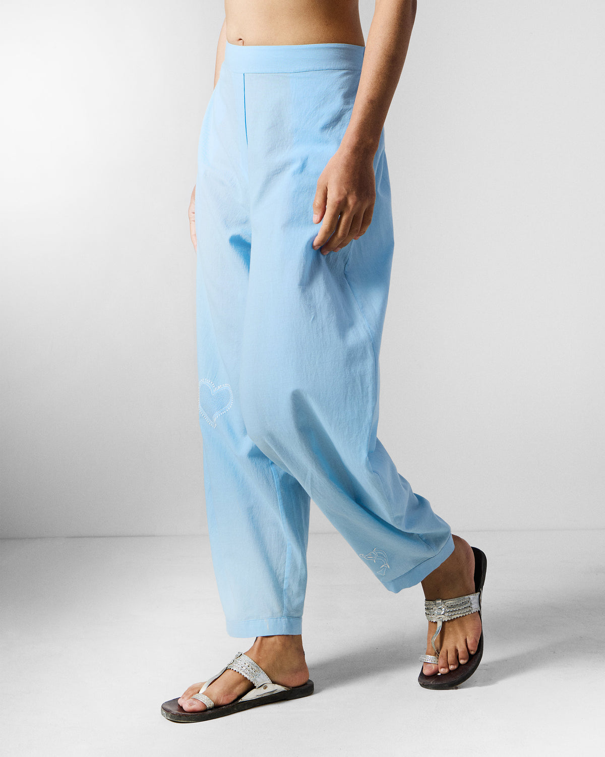Side view of ice blue Aaira Pants with white heart embroidery.