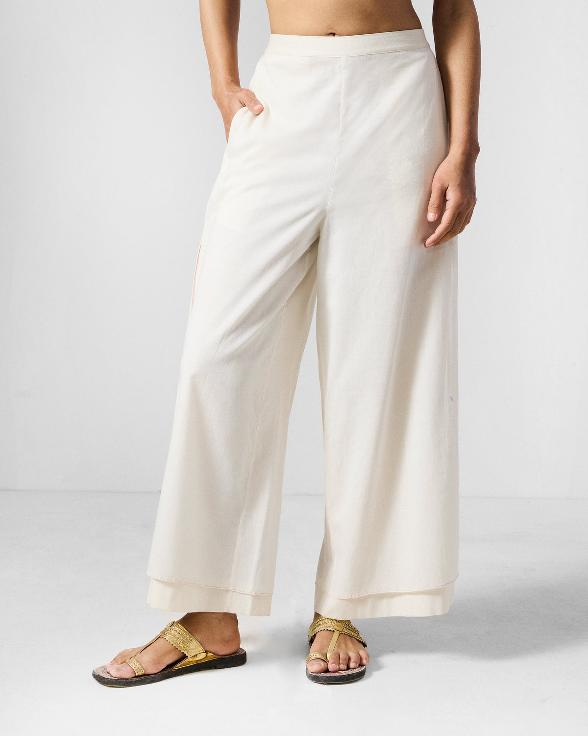 Person wearing ivory wide-leg Breeze pants with a layered hem.
