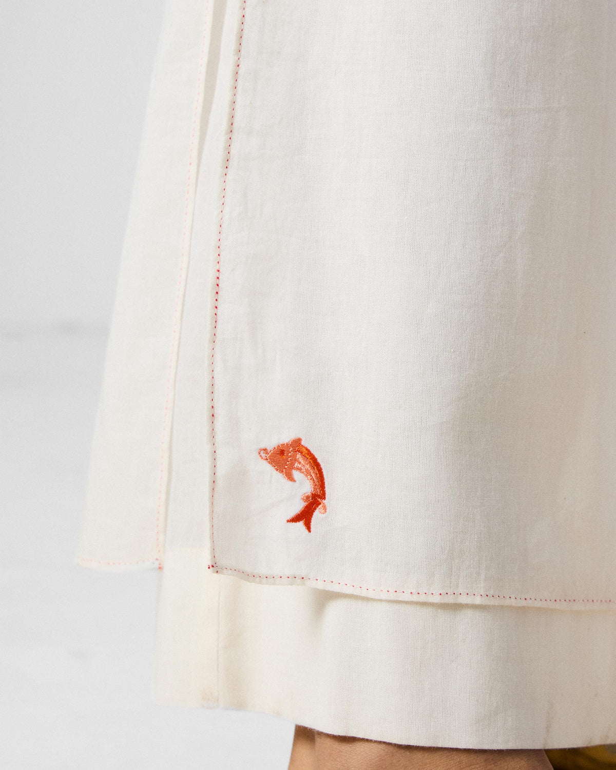 Close-up of a red fish embroidery on ivory Breeze pants.