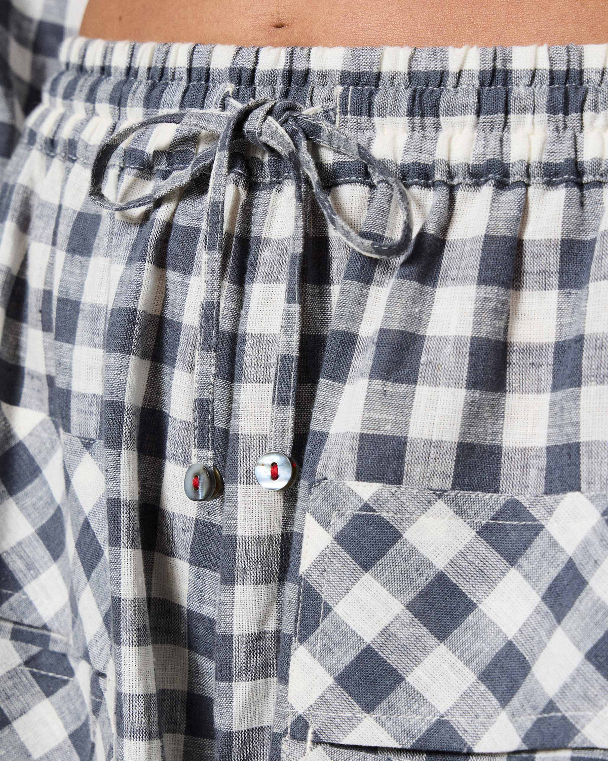 Close-up of the drawstring waist on grey and white checked Yoka trousers.