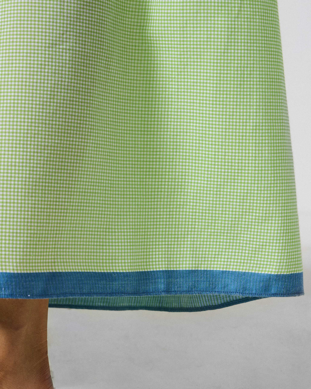 Close-up of light green and white check Paperbag Pants showing a blue hem border.