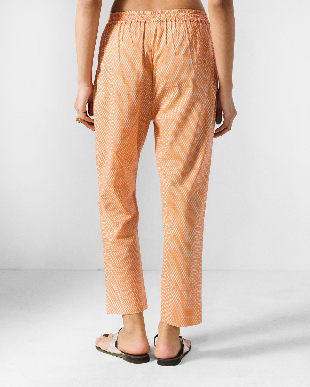 Back of orange printed Perch pants worn by a person.