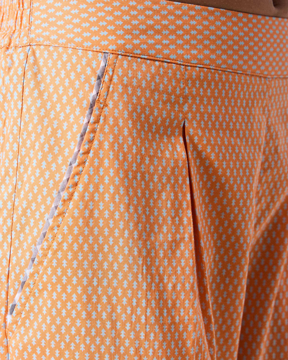 Close-up of the pleat and pocket on orange printed Perch pants.