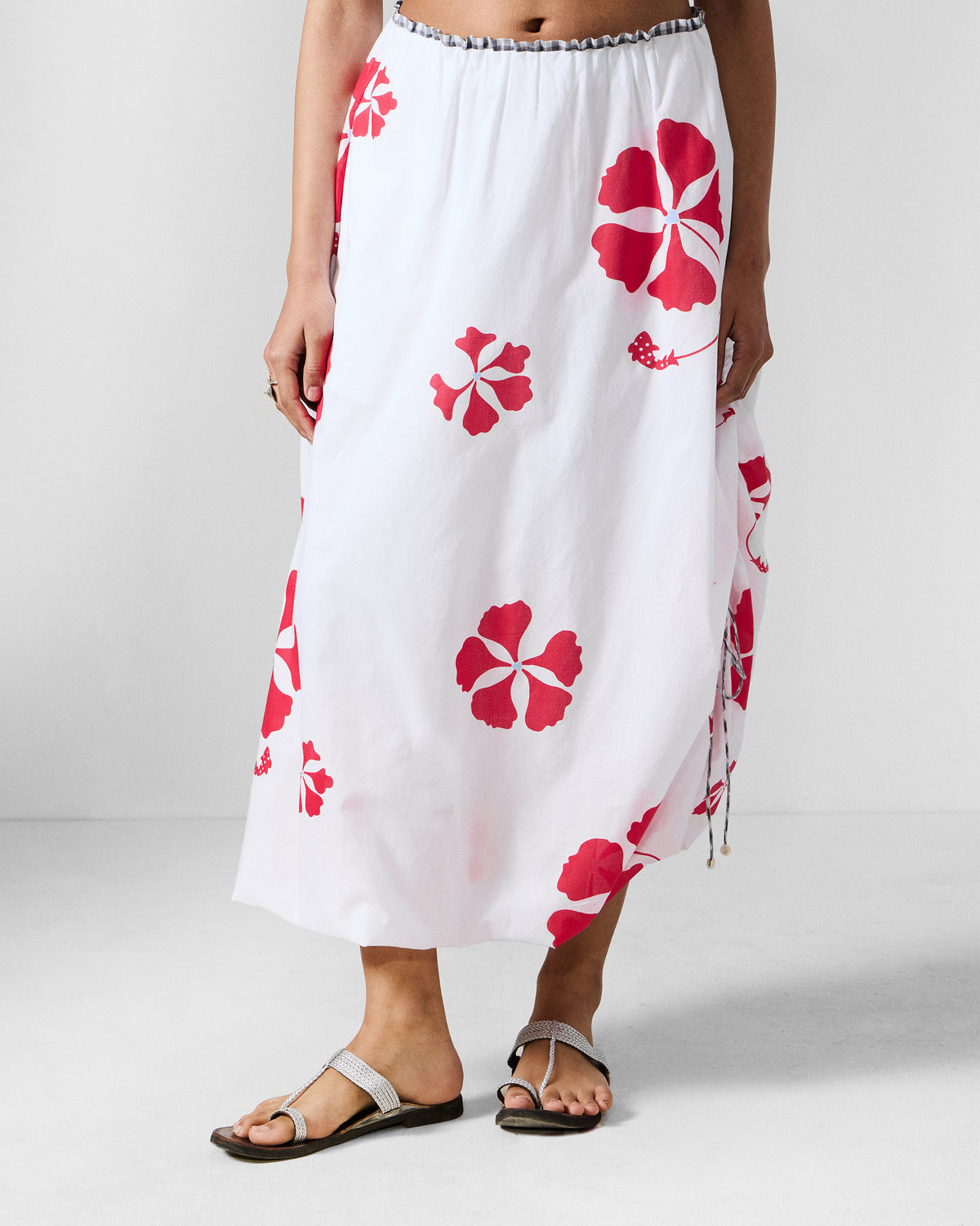 Person wearing a white Billow Skirt with a red gulmohar print.