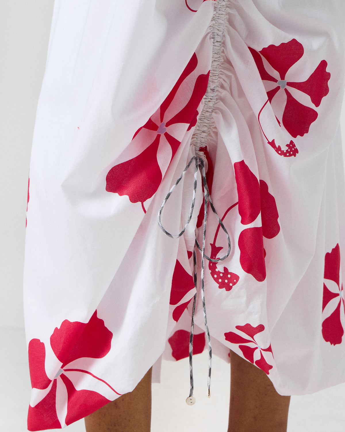 Close-up of a white Billow Skirt showing the red floral print and drawstring.