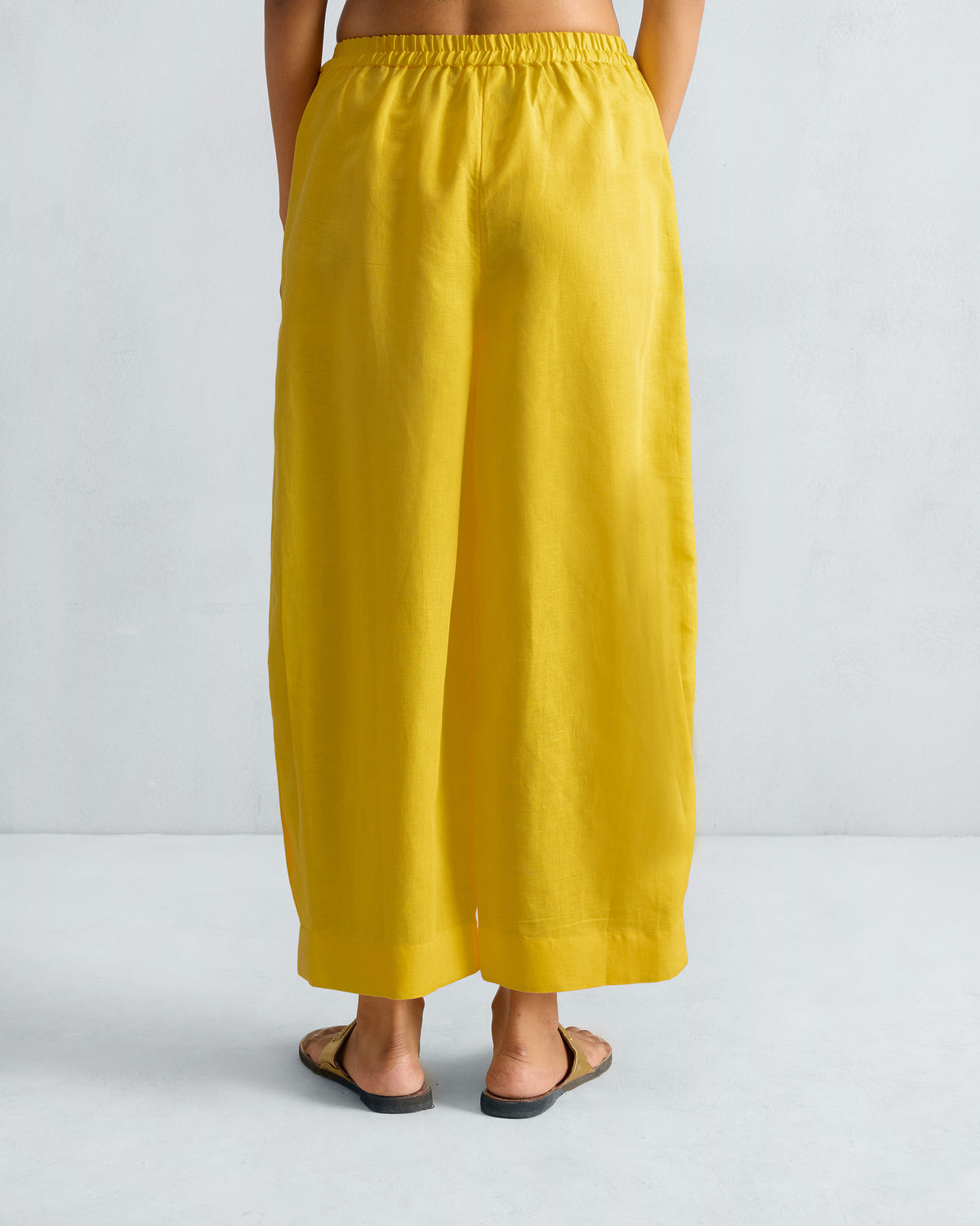 Back of yellow Serene pants with an elastic waistband and cropped wide legs.