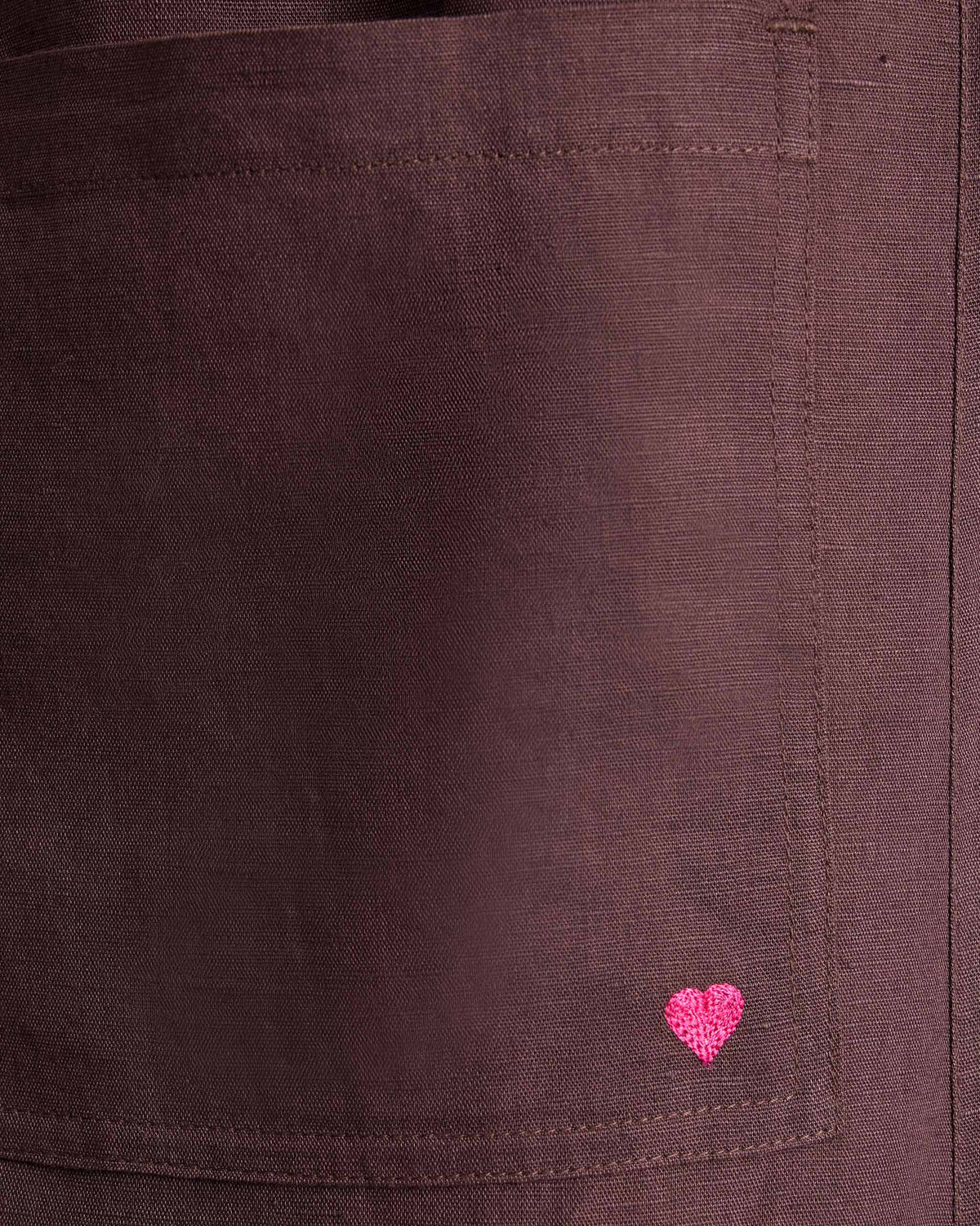 Close-up of chocolate plum Serene pants with a pink embroidered heart on the pocket.