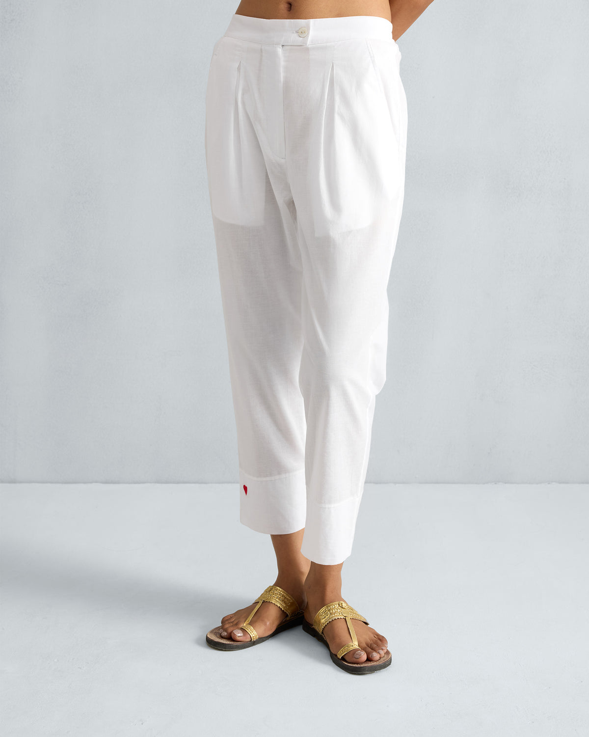 White Narrow pants with front pleats and a red embroidered heart at the cuff.