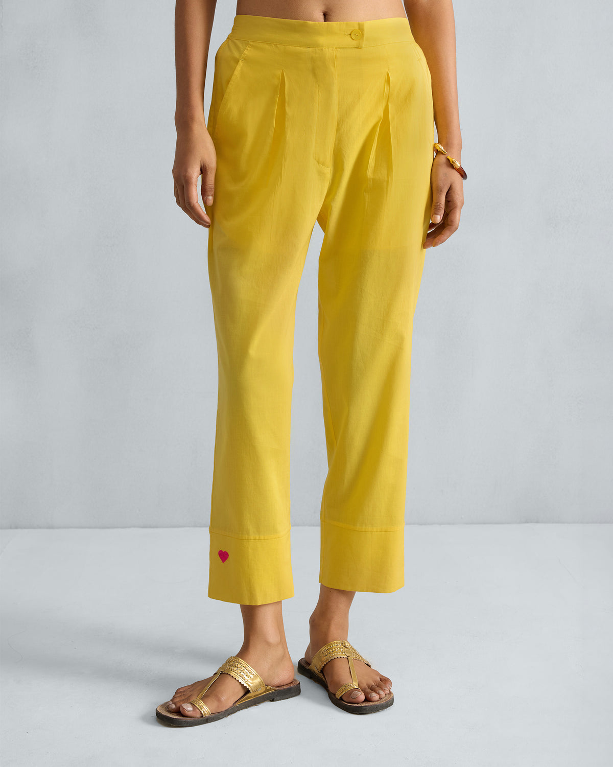 Person wearing yellow Narrow pants with front pleats and a red heart at the hem.