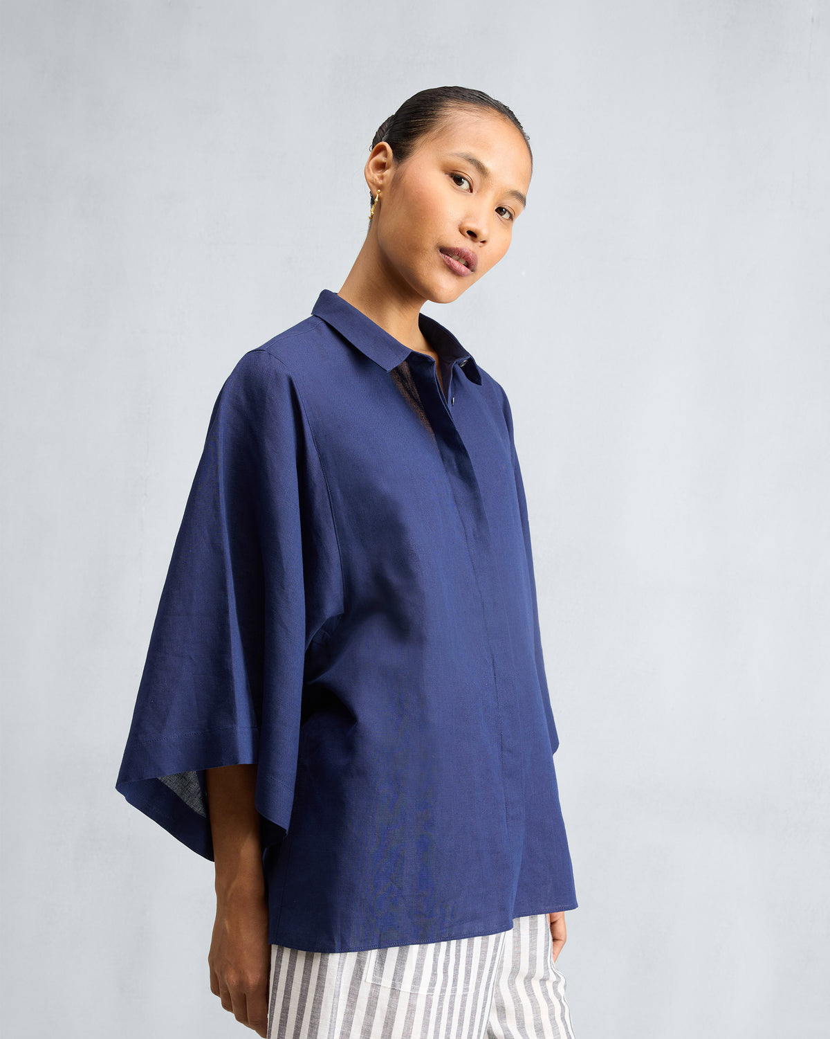 Person wearing an ink blue drop armhole shirt with wide sleeves.