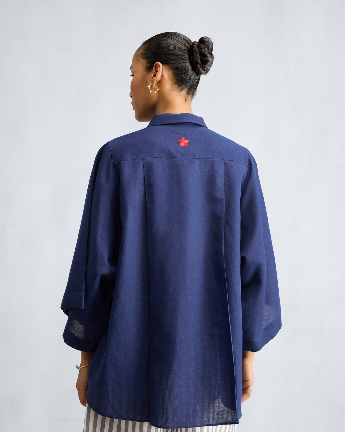 Back of an ink blue shirt with a small red star on the yoke.