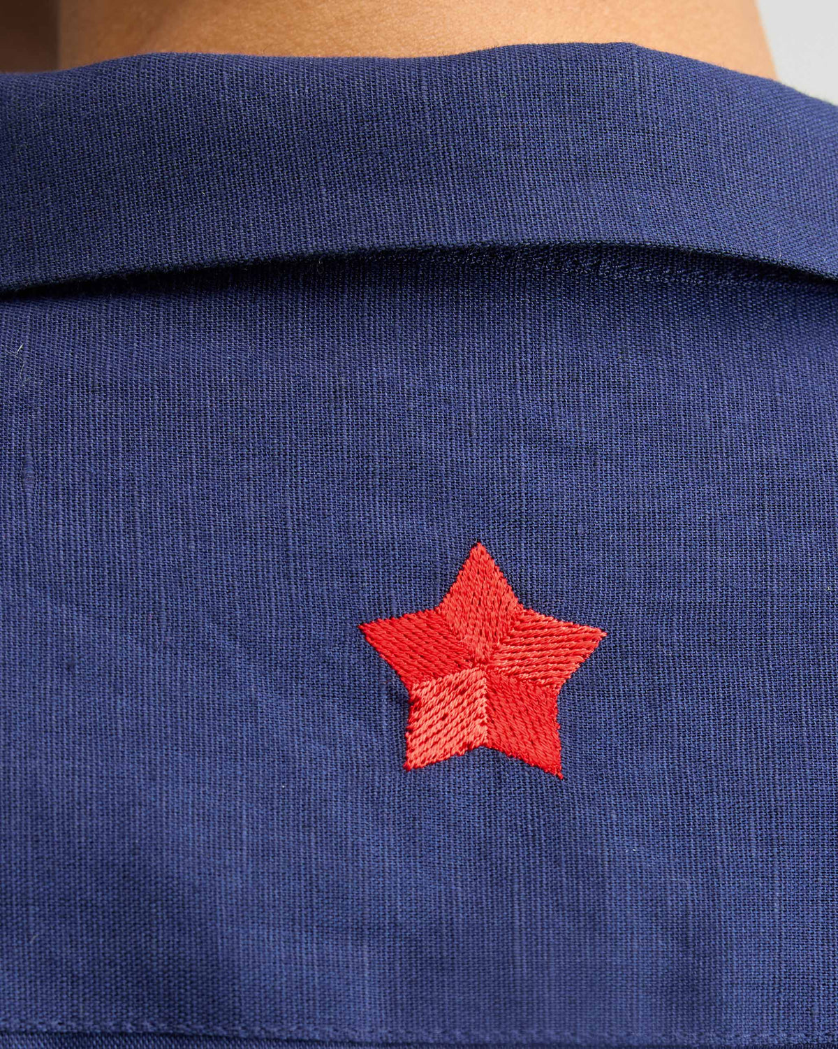 Close-up of an ink blue shirt with a red embroidered star.
