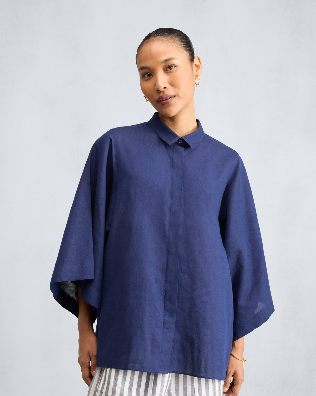 Person wearing an ink blue drop armhole shirt with wide sleeves.