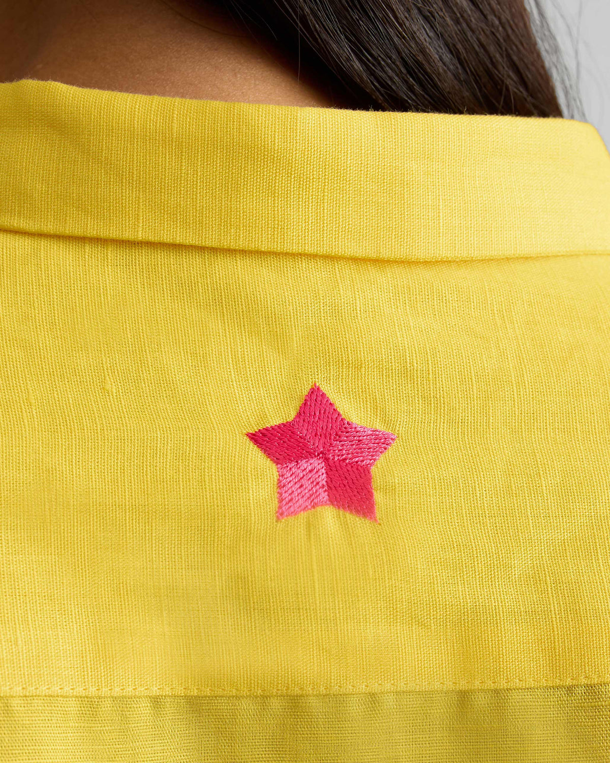 Close-up of a pink star on a yellow Drop Armhole Shirt.