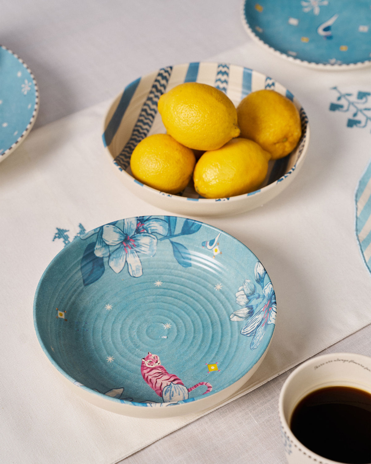 River Tiger shallow bowls on a table, one holding lemons and one showing a pink tiger.