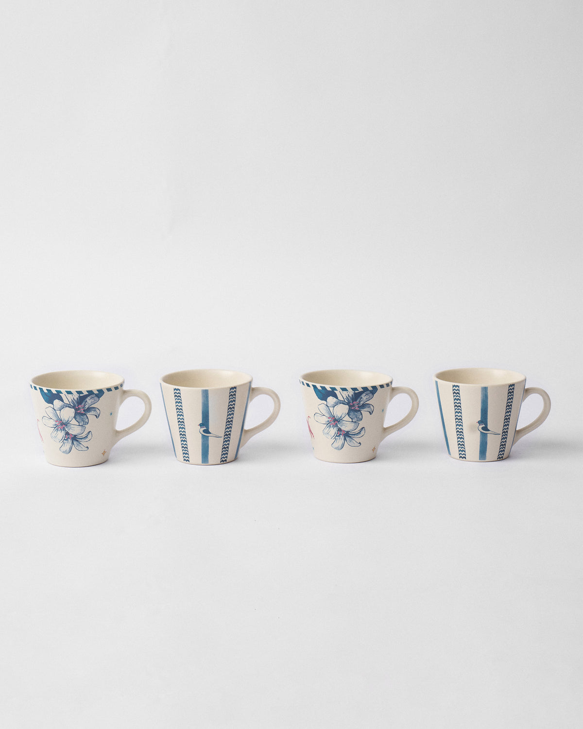 Set of four River Tiger espresso mugs with blue floral and striped bird designs.