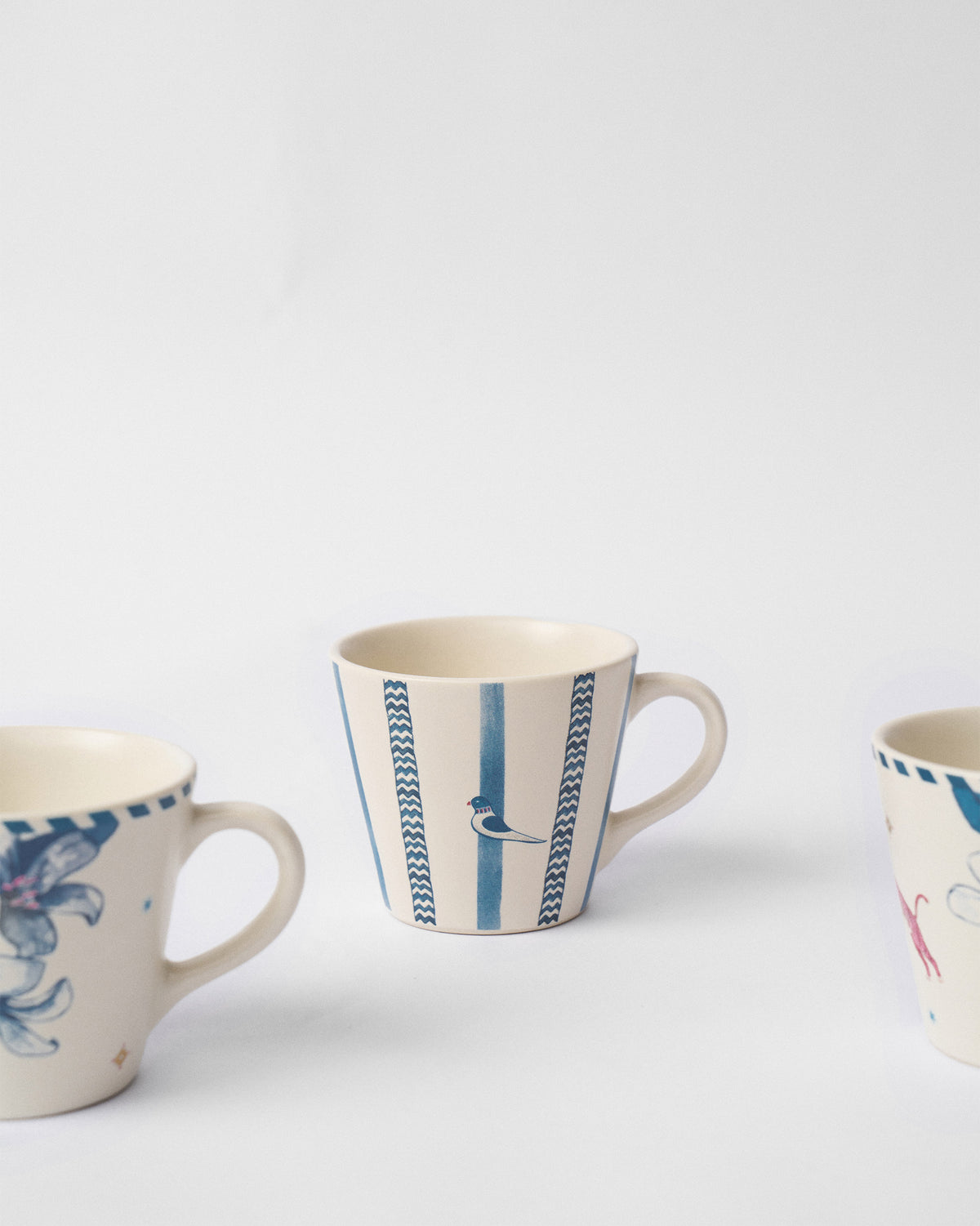 Close-up of a River Tiger espresso mug with blue stripes and a small bird.