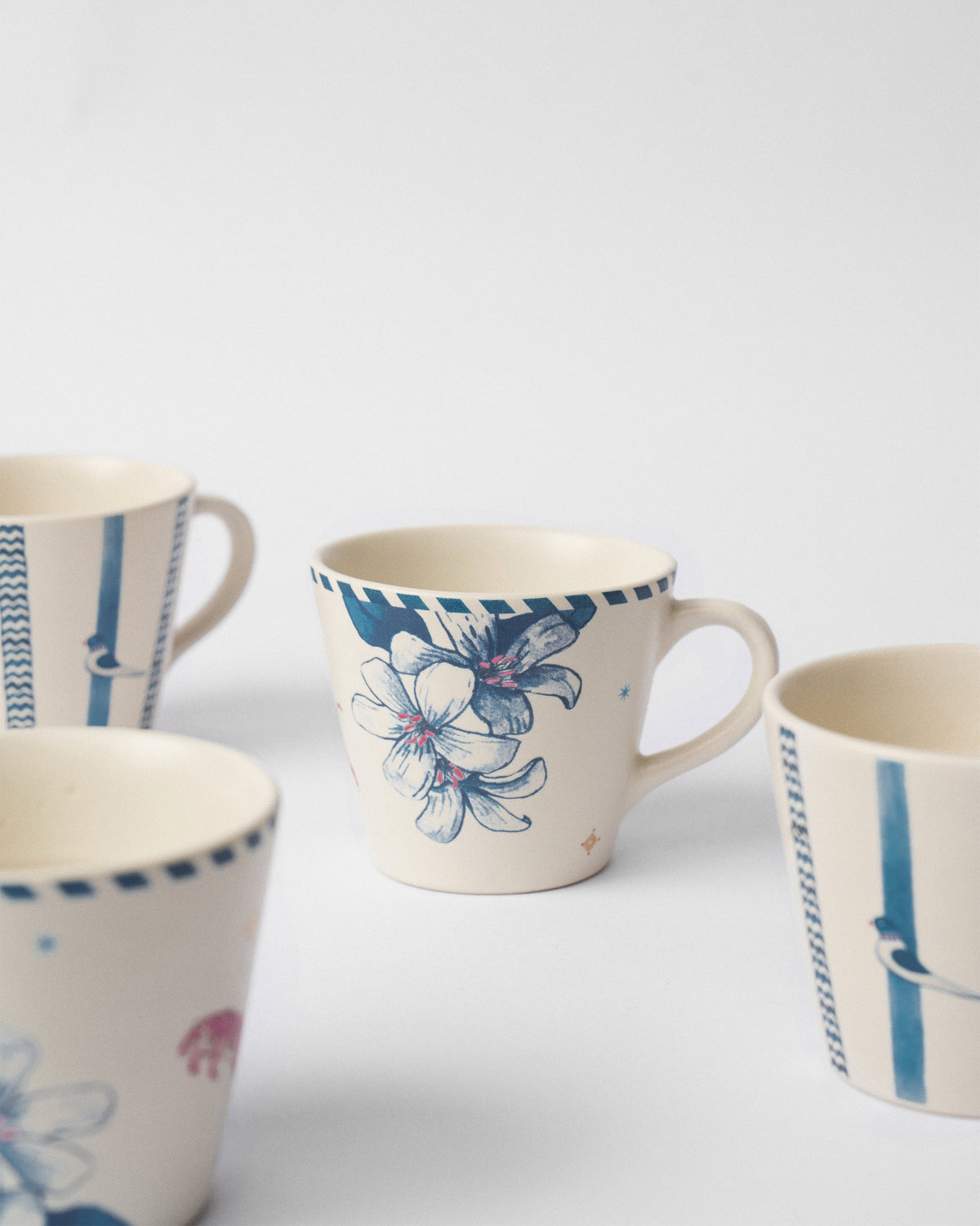 Close-up of a River Tiger espresso mug with blue lily motifs among the set.
