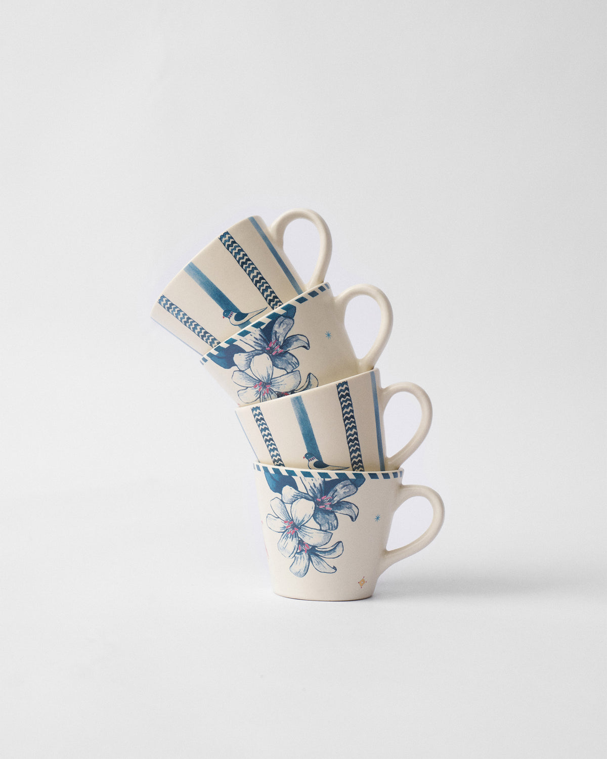 Stacked River Tiger espresso mugs alternating blue floral and striped bird designs.